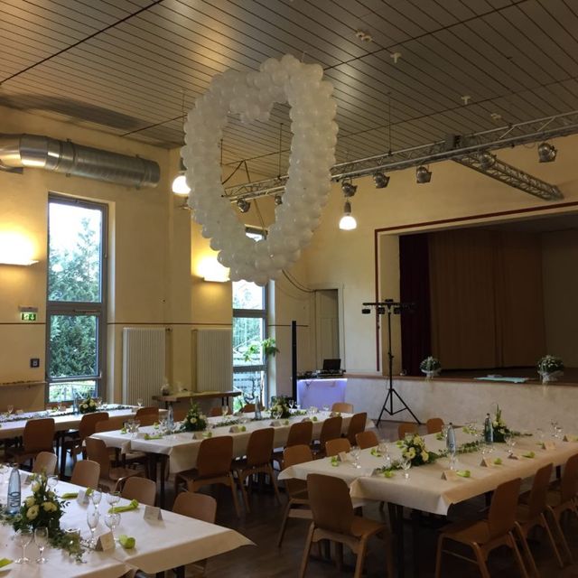 geschmückter Saal mit Bühne für eine Hochzeit